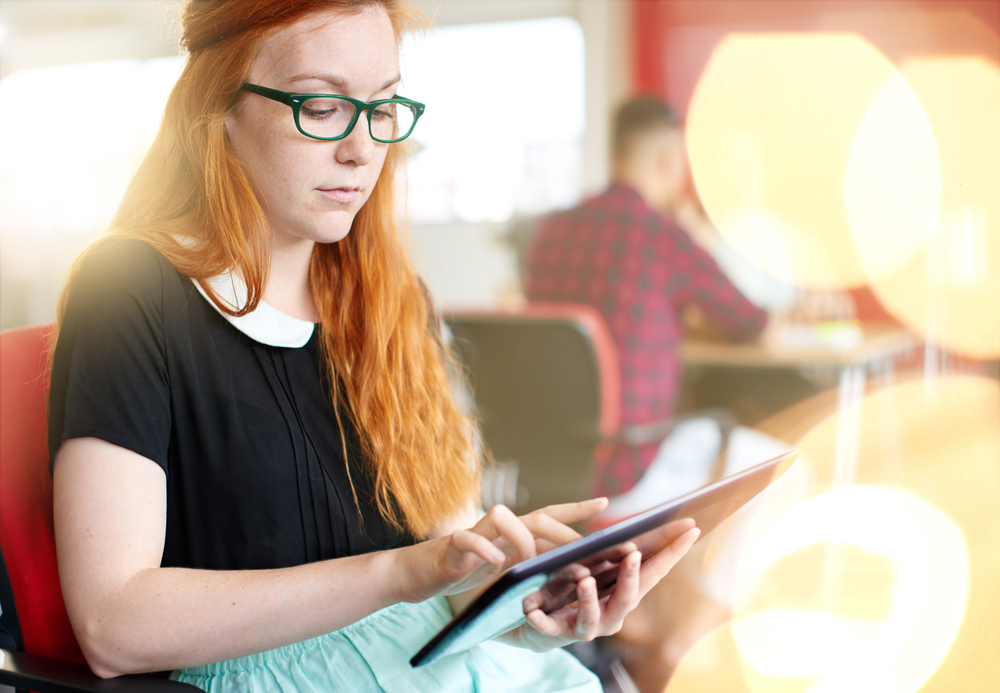 Confident female designer working on a digital tablet in red creative office space