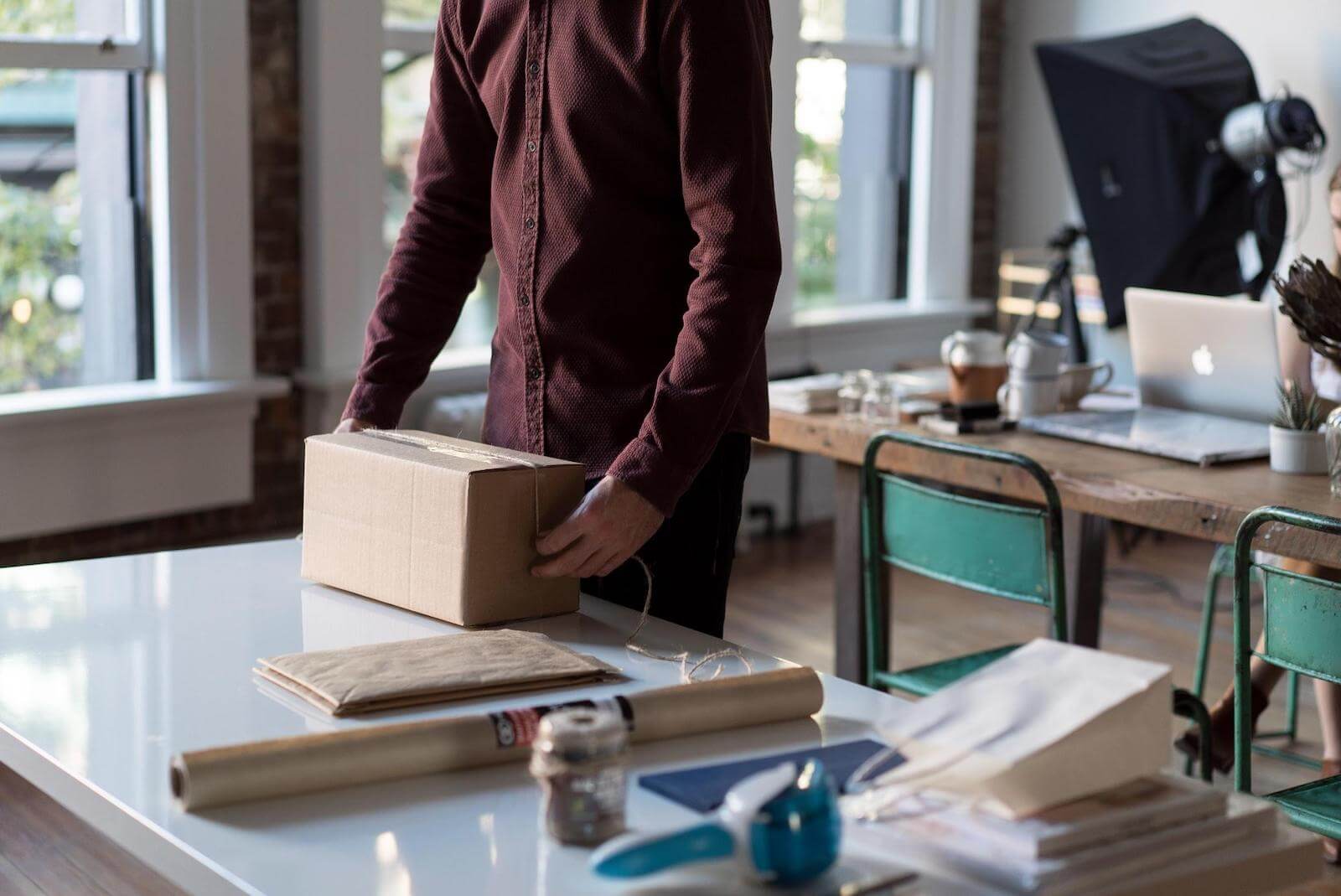 Multi Channel Inventory Sync: A man is closing a cardboard box to get it ready for delivery.